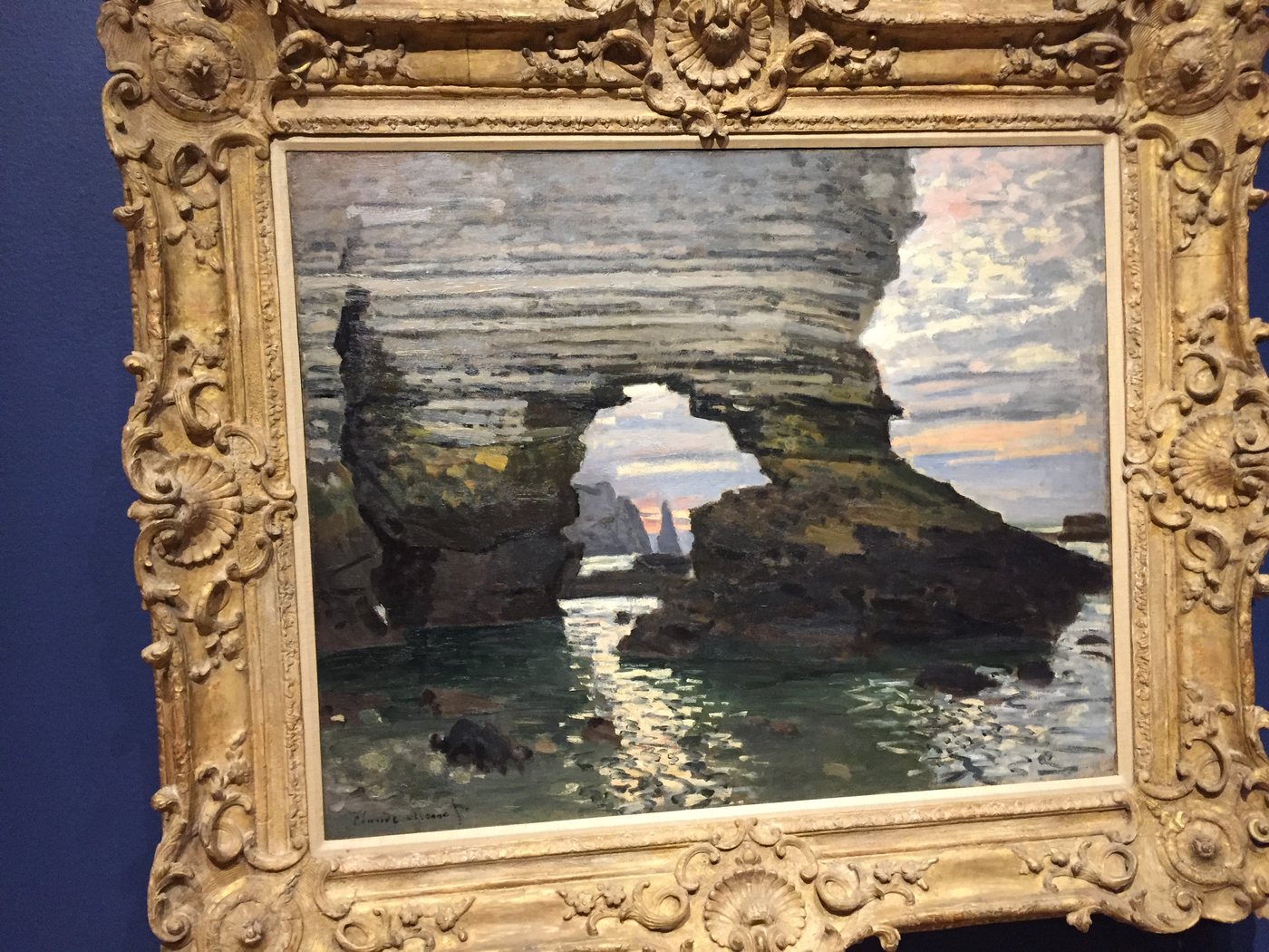 A painting of a sea arch in an ornate gold frame