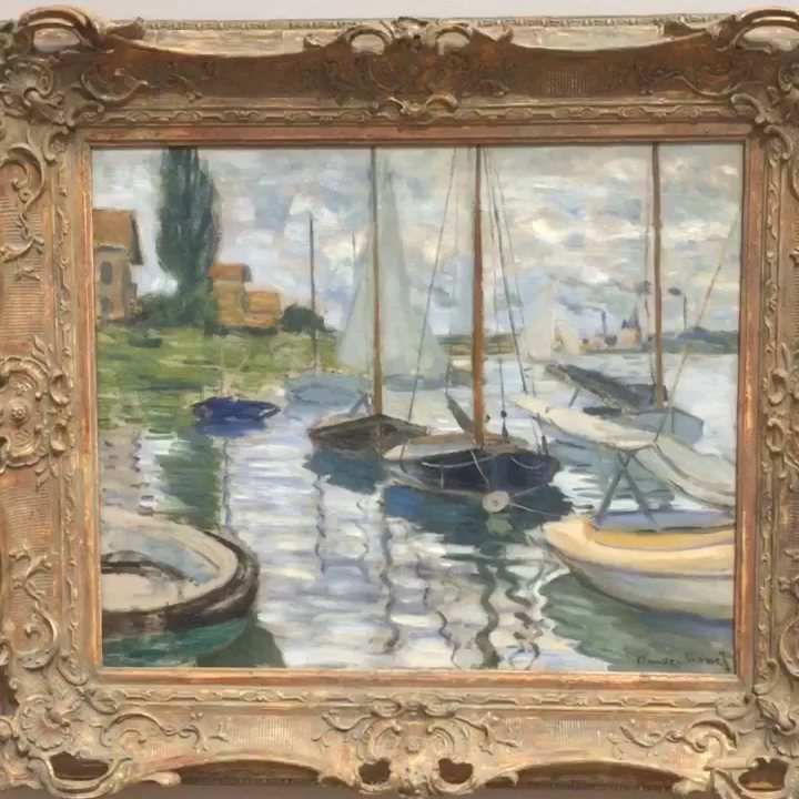 A painting of sailboats moored in a harbour, in a carved frame