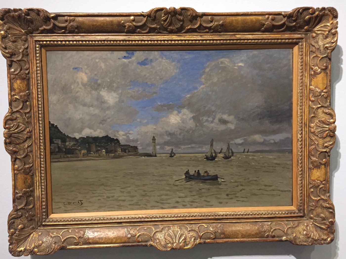 A grey harbour painting with small boats, in a gold frame