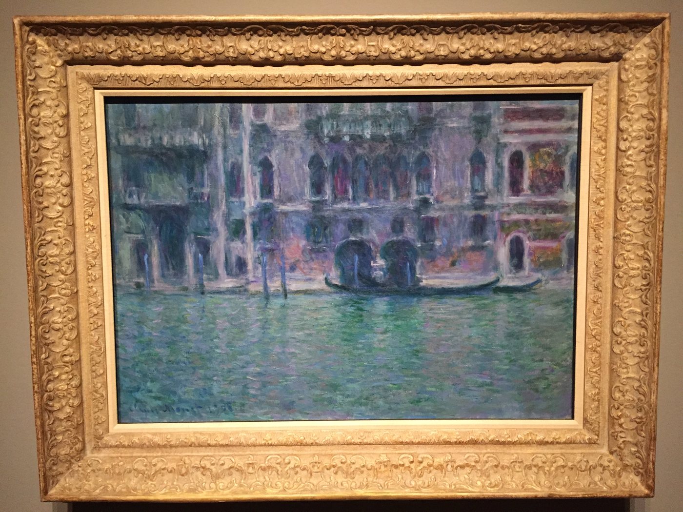 A painting of a Venetian palace on the water in a gold frame