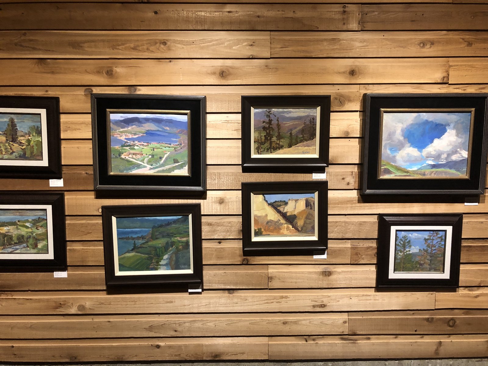Framed Okanagan landscapes hung on a rough cedar wall at Covert Farms
