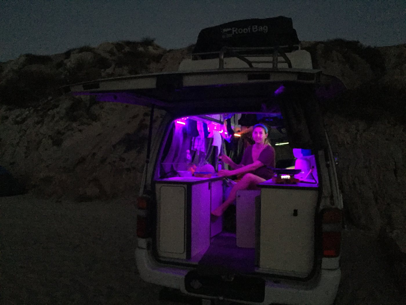 The back of the van open at night, lit purple inside